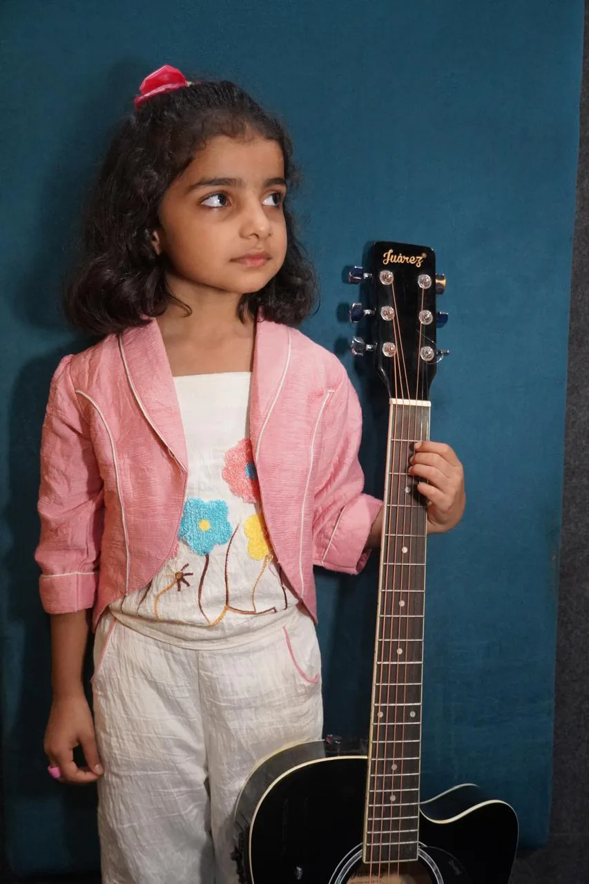 Young academy student posing with an acoustic guitar